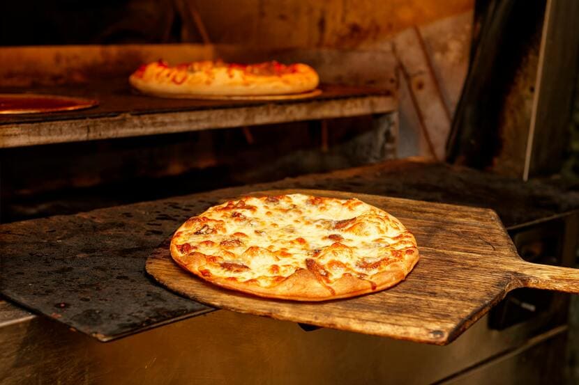 Pizza sendo colocada dentro do forno a lenha melhor-tipo-de-forno-para-pizzaria-saipos-sistema-para-restaurante