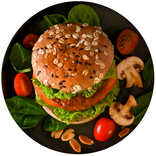 imagem de um hambúrguer vegano, com cogumelos e frutas verdes ao redor.