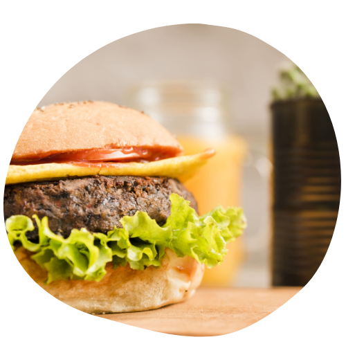 imagem de um hambúrguer vegano com em uma tábua de madeira e elementos visuais do produtos e chamando a tenção para o hambúrguer. o hambúrguer é feito com proteína de soja, alface, queijo vegano e molho rose.