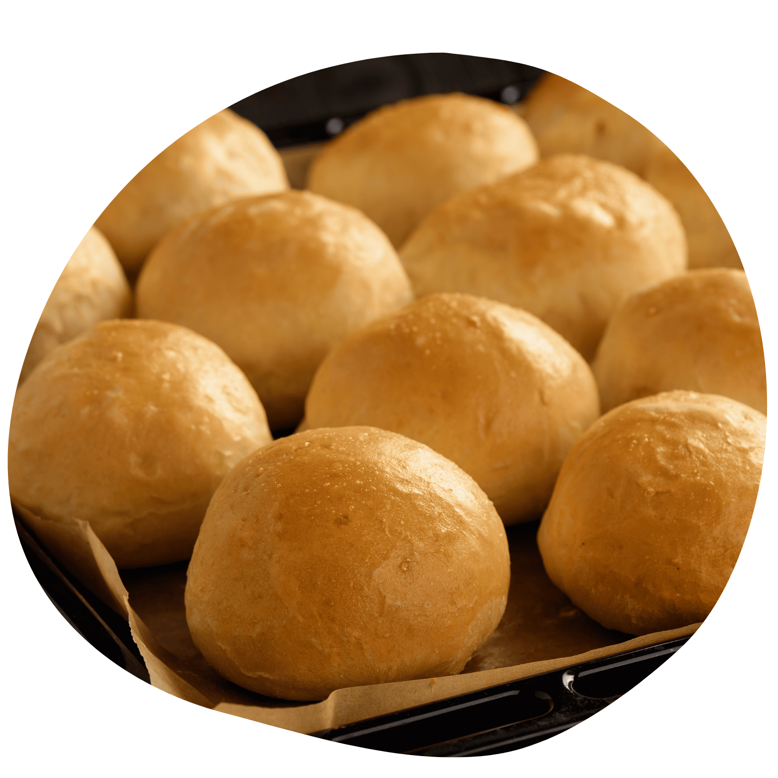 Vários pães de batata redondos e dourados recém-assados dispostos em uma assadeira. Superfície brilhante e textura macia aparente.