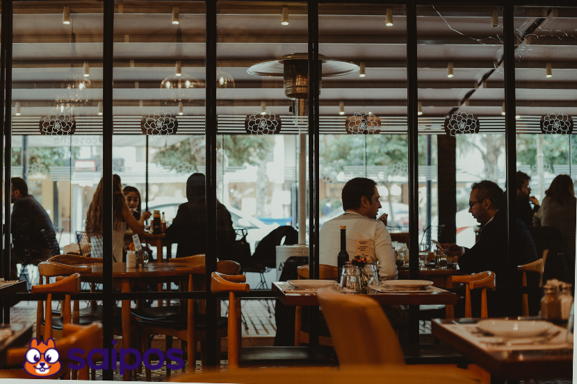 Foto ampla de um restaurante com várias pessoas sentadas em diversas mesas.