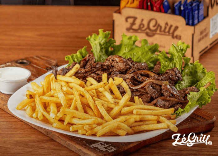 Porção de batatas fritas com carne acebolada do Zé Grill, cliente Saipos